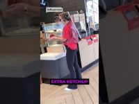 Woman holds ketchup in fast-food restaurant.