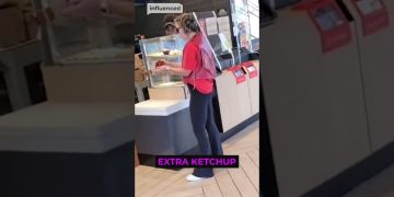 Woman holds ketchup in fast-food restaurant.