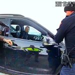 Police officers inspecting car during traffic stop.