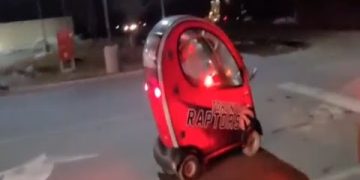 Small red car driving at night