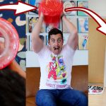 Man enthusiastically inflates red balloon toy indoors.