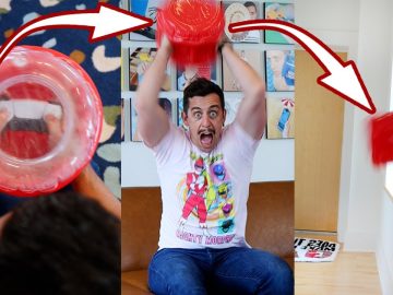 Man enthusiastically inflates red balloon toy indoors.