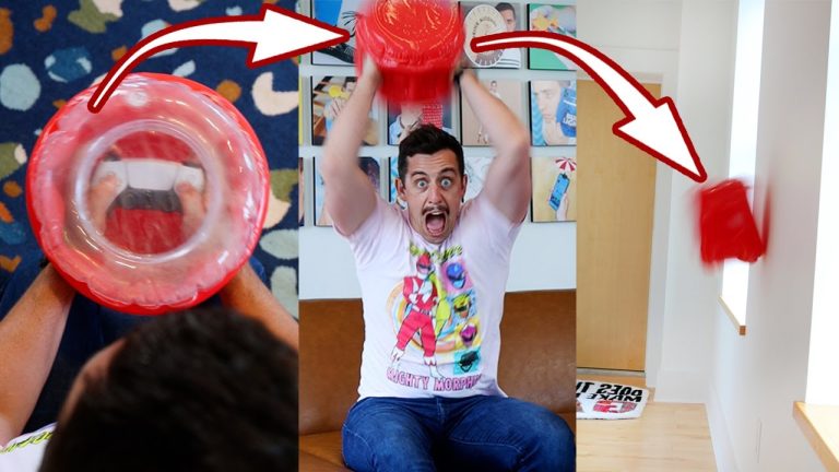 Man enthusiastically inflates red balloon toy indoors.