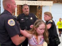 Woman arrested near lemonade stand, child in background.