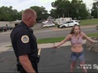 Police officer talking to distressed woman on street.