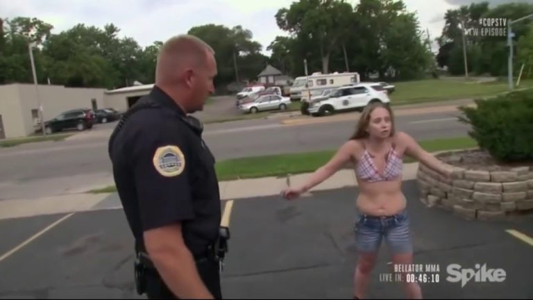 Police officer talking to distressed woman on street.