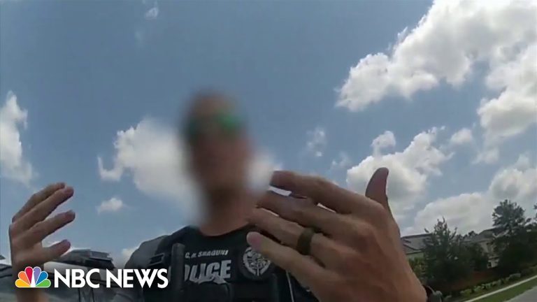 Police officer with blurred face gesturing outdoors.