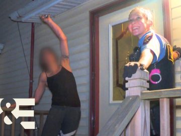 Police officer smiling on porch with man nearby.