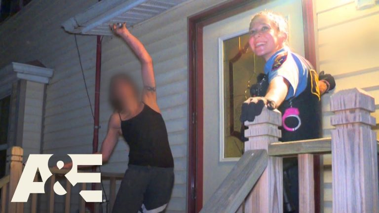 Police officer smiling on porch with man nearby.