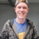 Smiling person wearing a camo hoodie and cap