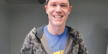 Smiling person wearing a camo hoodie and cap