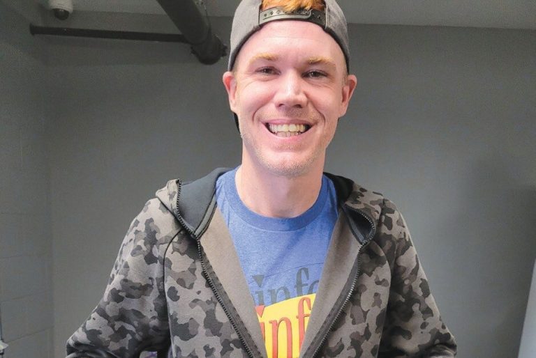 Smiling person wearing a camo hoodie and cap