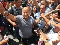 Man surrounded by crowd waving and cheering