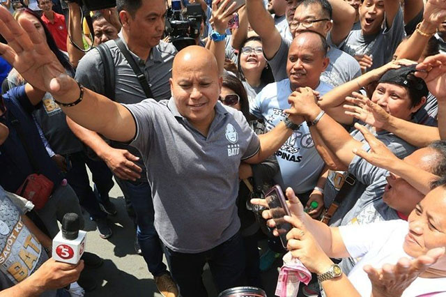 Man surrounded by crowd waving and cheering