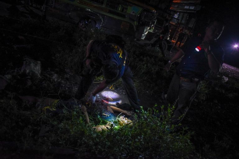 People investigating dark outdoor scene with flashlights.