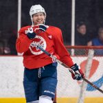 Hockey player practicing on ice rink, smiling.