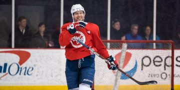 Hockey player practicing on ice rink, smiling.