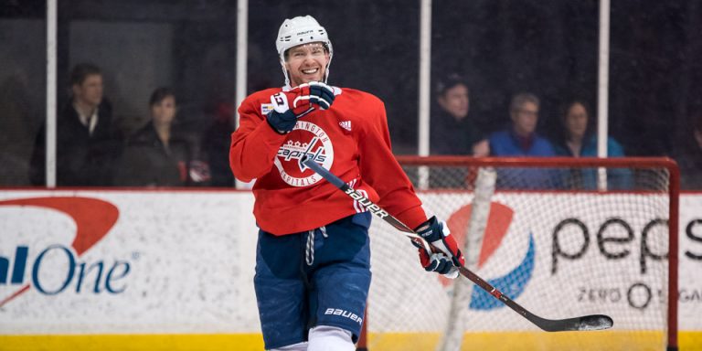 Hockey player practicing on ice rink, smiling.