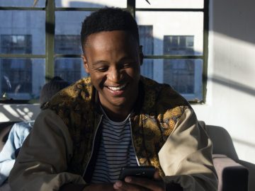 Man smiling while looking at his phone indoors.