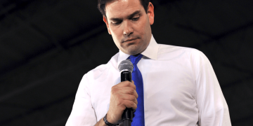 Man holding microphone, looking down thoughtfully.