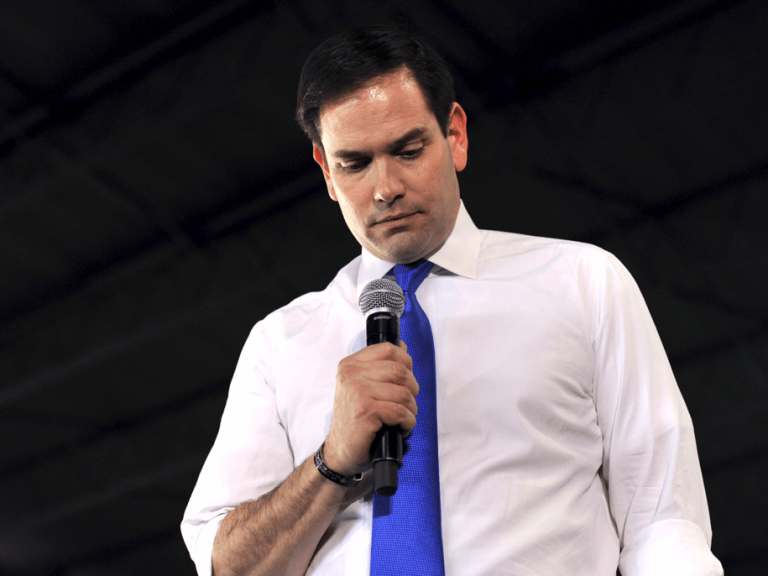 Man holding microphone, looking down thoughtfully.