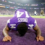 American football player kneeling on field, celebrating.