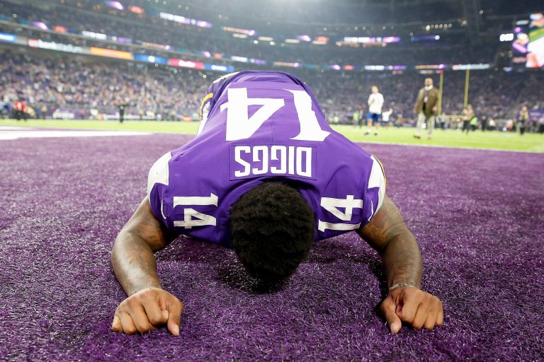 American football player kneeling on field, celebrating.