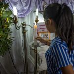 Woman lighting candle at a memorial service.