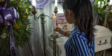 Woman lighting candle at a memorial service.