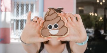 Person holding smiling poop emoji cookie