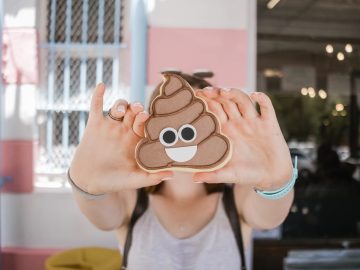 Person holding smiling poop emoji cookie