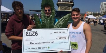 Three people holding large check at 420 Games.