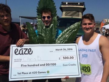 Three people holding large check at 420 Games.