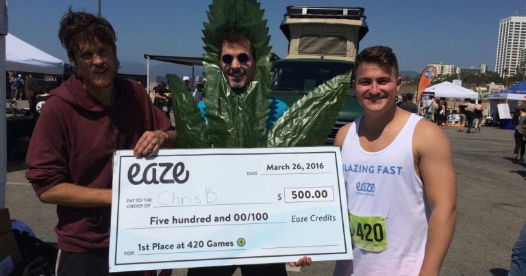 Three people holding large check at 420 Games.